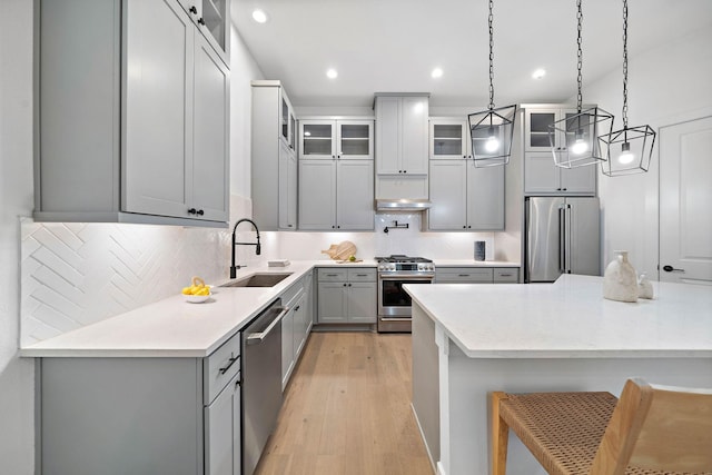 kitchen with light hardwood / wood-style flooring, decorative light fixtures, gray cabinetry, appliances with stainless steel finishes, and sink