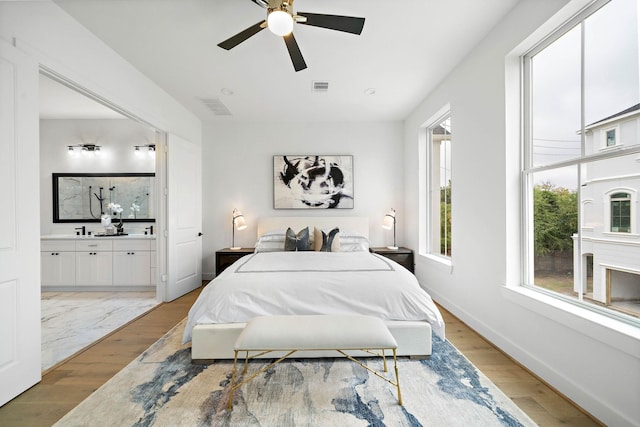 bedroom with ensuite bathroom, ceiling fan, and light wood-type flooring