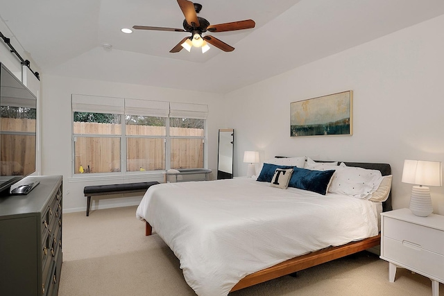 bedroom with ceiling fan, light colored carpet, a barn door, and a raised ceiling