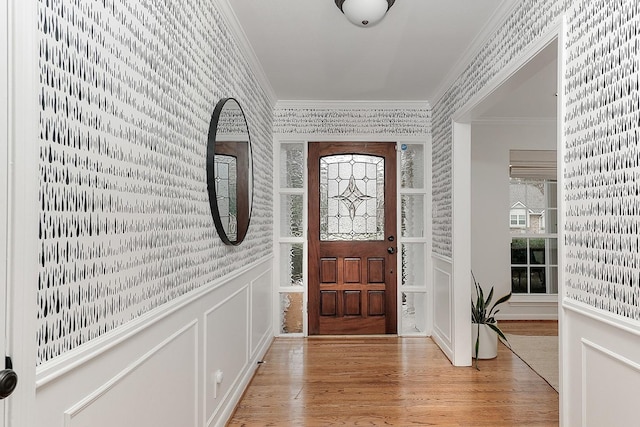 entryway with ornamental molding and light hardwood / wood-style floors