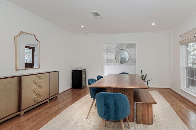 dining area with ornamental molding and light hardwood / wood-style flooring