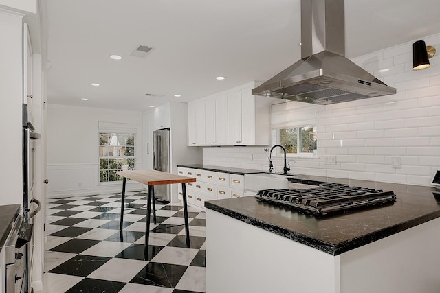 kitchen featuring kitchen peninsula, island exhaust hood, white cabinetry, appliances with stainless steel finishes, and sink