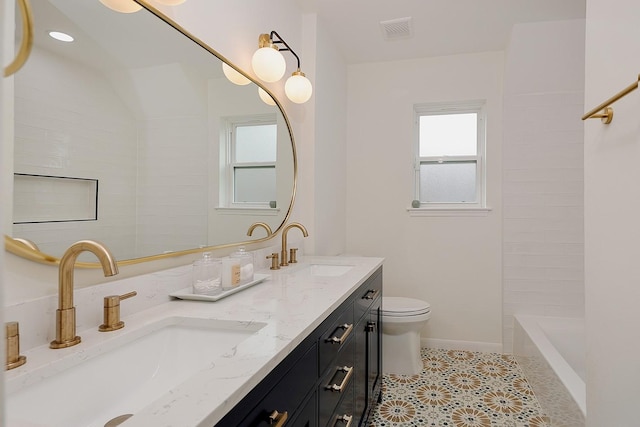 bathroom featuring toilet, vanity, tile patterned flooring, and a wealth of natural light