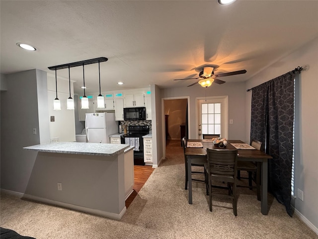 kitchen featuring decorative light fixtures, carpet floors, backsplash, black appliances, and white cabinetry