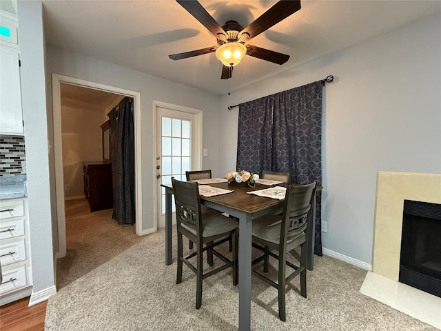 carpeted dining space with ceiling fan and a fireplace