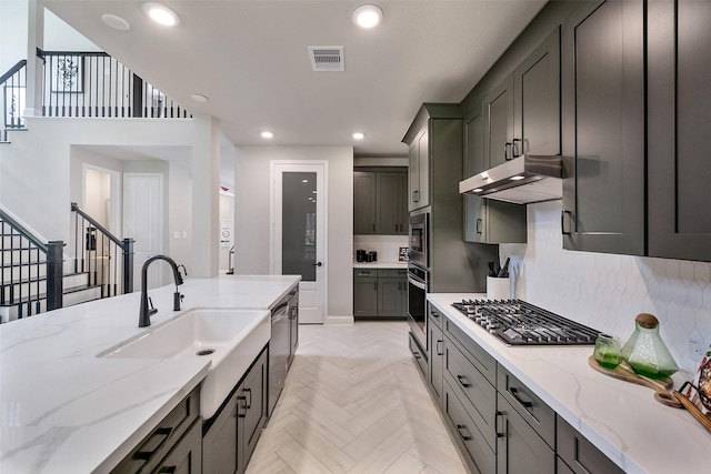 kitchen featuring light stone countertops, appliances with stainless steel finishes, light parquet floors, and sink