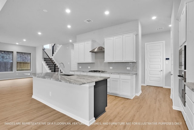 kitchen with sink, white cabinetry, a kitchen island with sink, and appliances with stainless steel finishes