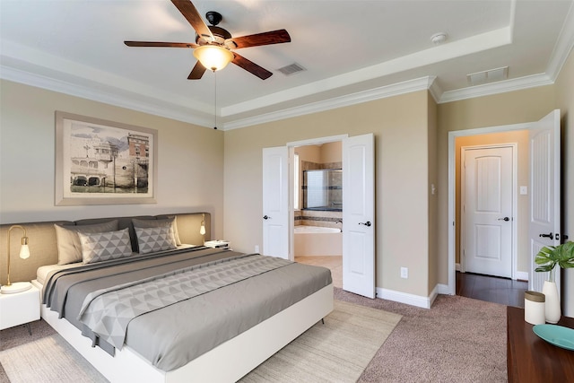 bedroom with a raised ceiling, ceiling fan, ornamental molding, carpet floors, and ensuite bath