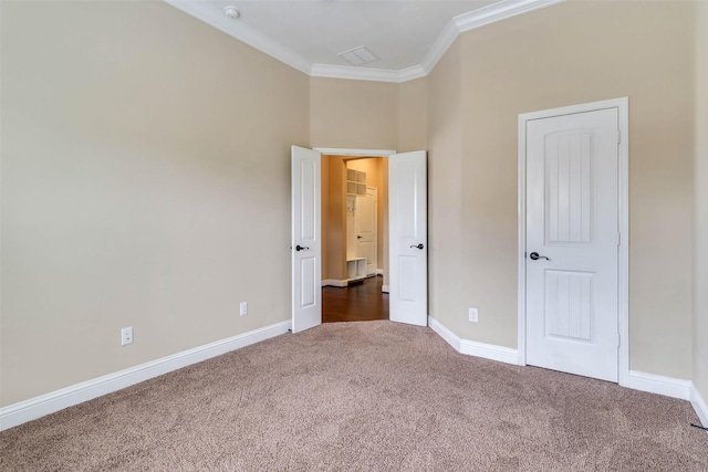 unfurnished bedroom featuring dark colored carpet and ornamental molding