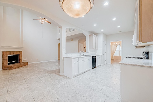 kitchen featuring white cabinetry, a brick fireplace, ceiling fan, and stove