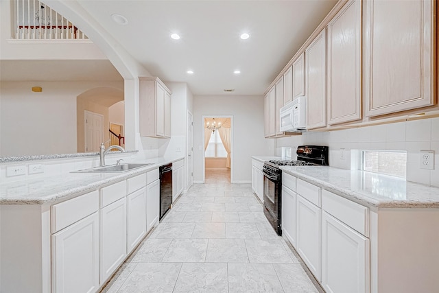 kitchen with sink, kitchen peninsula, light stone counters, and black appliances