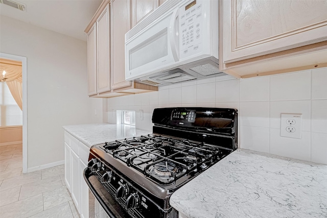 kitchen with tasteful backsplash, light stone counters, and black range with gas stovetop