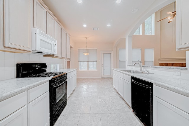 kitchen with decorative light fixtures, light stone countertops, sink, and black appliances