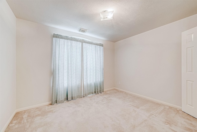 unfurnished room featuring light colored carpet and a textured ceiling