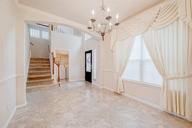 foyer featuring an inviting chandelier, crown molding, washing machine and dryer, and a wealth of natural light