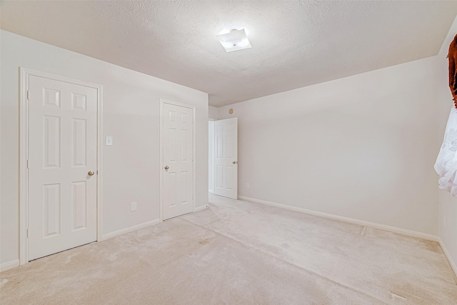 spare room with light carpet and a textured ceiling