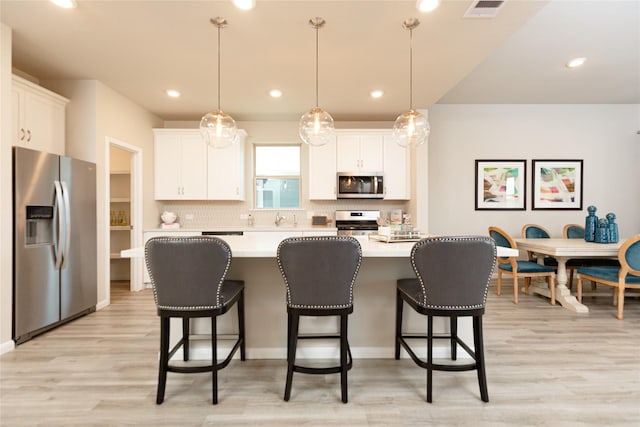 kitchen featuring white cabinets, appliances with stainless steel finishes, and pendant lighting