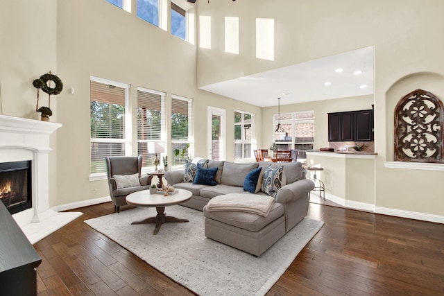 living room with a towering ceiling, dark wood-type flooring, and ceiling fan