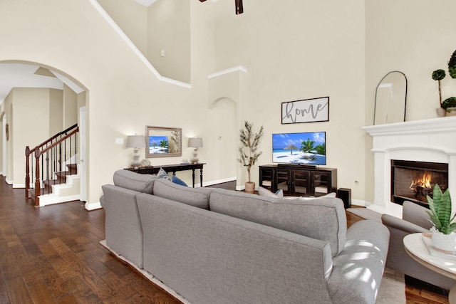 living room with ceiling fan, dark wood-type flooring, and a towering ceiling