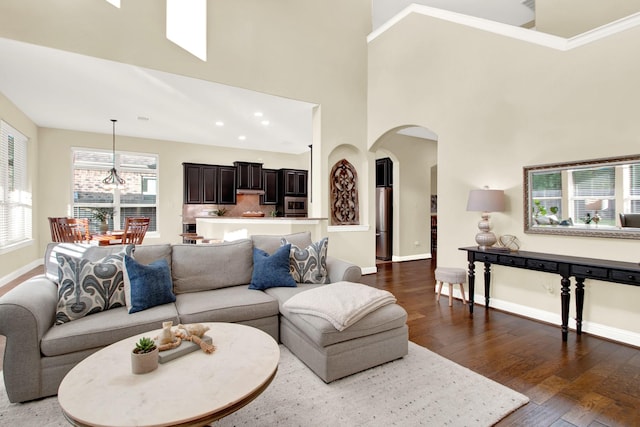 living room with a high ceiling, an inviting chandelier, and dark hardwood / wood-style floors