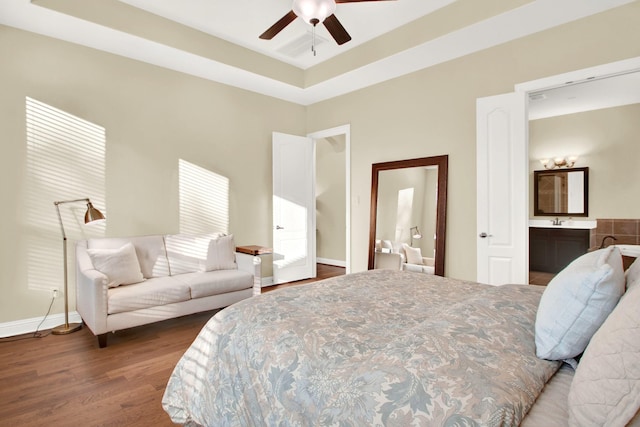 bedroom with ceiling fan, ensuite bathroom, a raised ceiling, and dark hardwood / wood-style floors