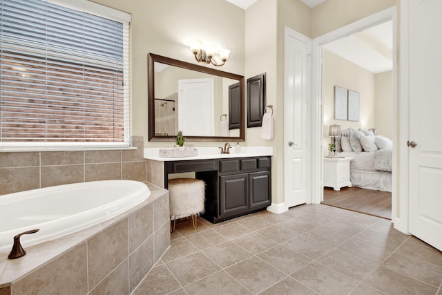 bathroom with tile patterned flooring, vanity, and tiled tub