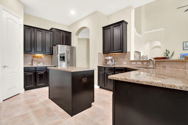 kitchen featuring sink, light stone counters, tasteful backsplash, and stainless steel fridge with ice dispenser