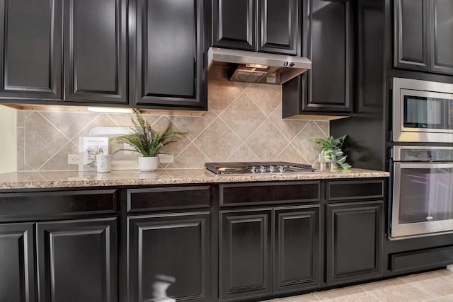 kitchen with light stone counters, stainless steel appliances, and decorative backsplash