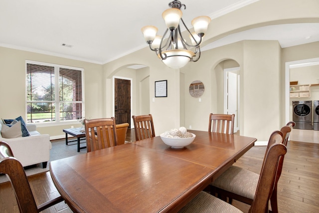 dining room with ornamental molding, an inviting chandelier, washing machine and clothes dryer, and wood-type flooring