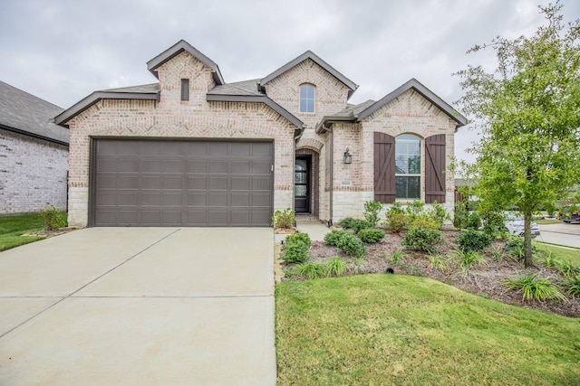 french provincial home featuring a front yard and a garage