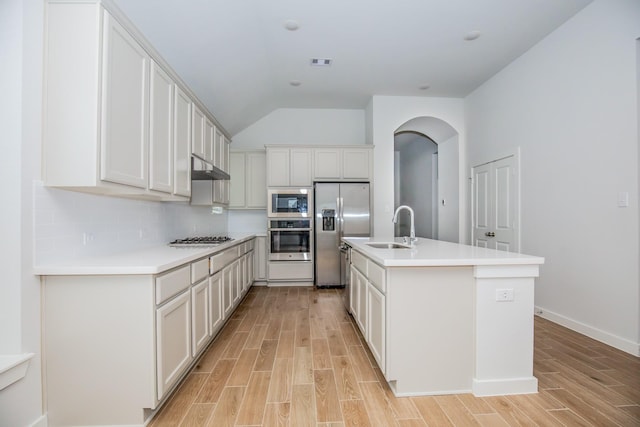 kitchen with decorative backsplash, a kitchen island with sink, white cabinets, appliances with stainless steel finishes, and sink