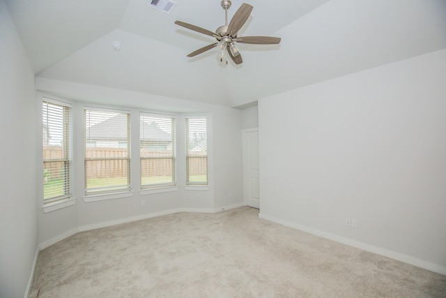 spare room with ceiling fan, light colored carpet, and vaulted ceiling