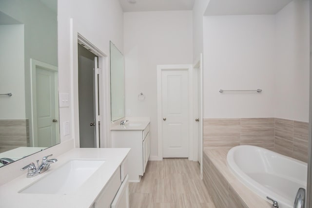 bathroom featuring vanity and tiled tub