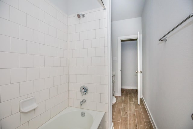 bathroom featuring toilet and tiled shower / bath