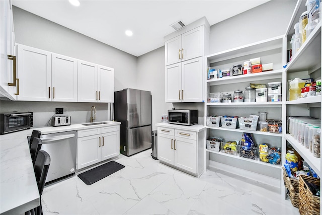 kitchen featuring sink, light stone countertops, white cabinets, and appliances with stainless steel finishes