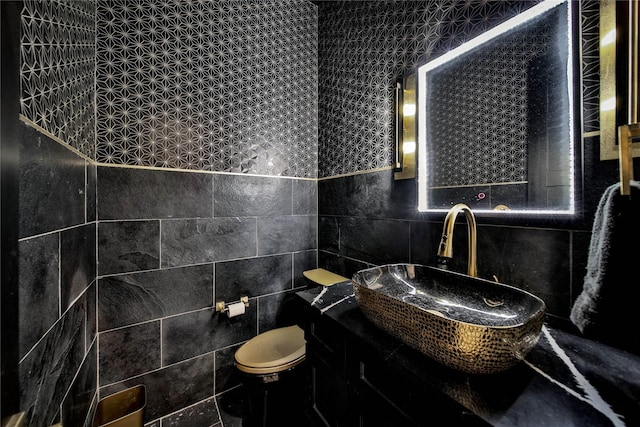 bathroom featuring sink, tile walls, and toilet