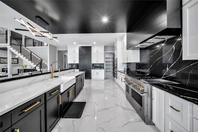 kitchen with sink, white cabinetry, stainless steel appliances, light stone counters, and wall chimney exhaust hood