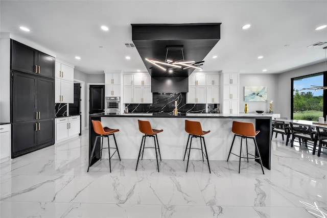 kitchen with tasteful backsplash, oven, a breakfast bar area, and white cabinets