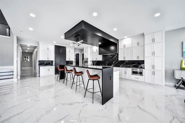 kitchen featuring a breakfast bar, a center island, decorative backsplash, and white cabinets