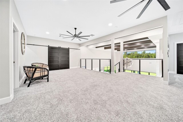 sitting room featuring ceiling fan, a barn door, and carpet floors