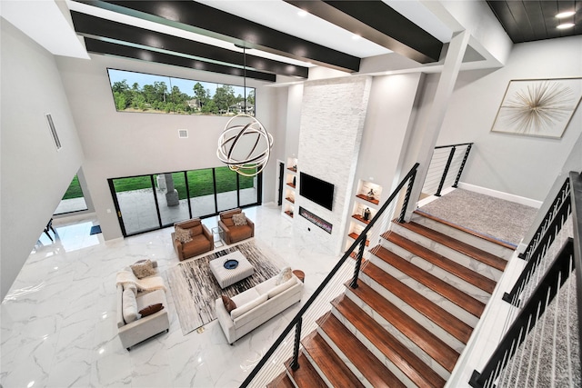 living room with a stone fireplace and beamed ceiling