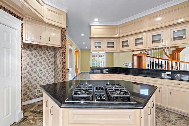 kitchen with arched walkways, cream cabinetry, crown molding, black gas cooktop, and a kitchen island