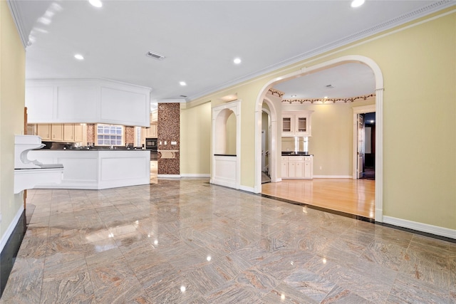 unfurnished living room with ornamental molding, arched walkways, marble finish floor, and baseboards