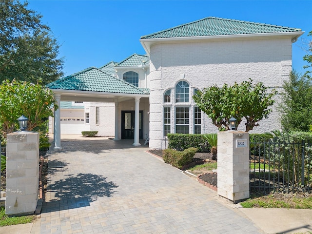 view of front of home featuring brick siding, decorative driveway, a tile roof, and fence