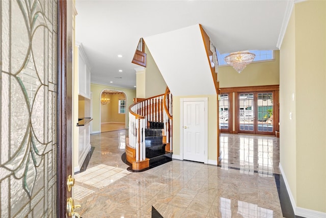 foyer featuring arched walkways, baseboards, stairs, and a notable chandelier