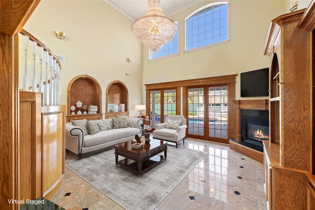 living area with marble finish floor, a notable chandelier, stairway, ornamental molding, and a glass covered fireplace