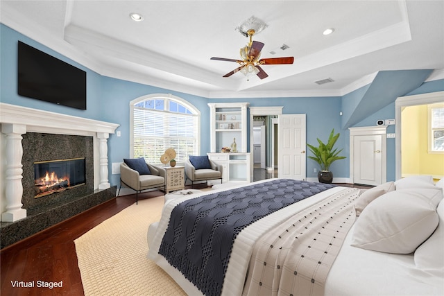 bedroom featuring a raised ceiling, visible vents, a premium fireplace, and wood finished floors