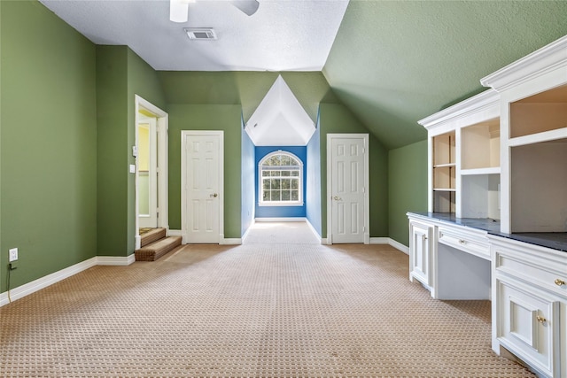 bonus room featuring light colored carpet, visible vents, vaulted ceiling, a textured ceiling, and baseboards