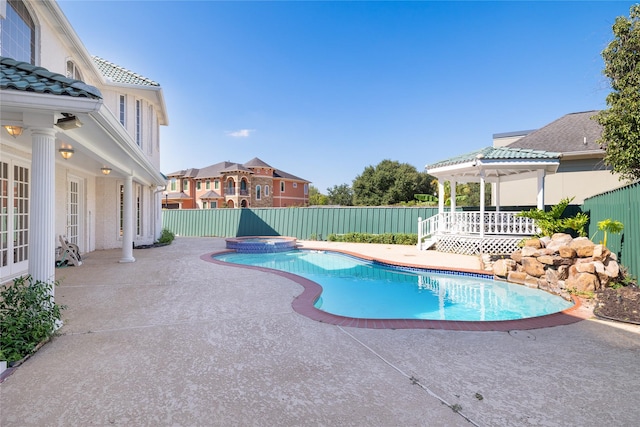 view of pool featuring a fenced backyard, a pool with connected hot tub, french doors, and a patio