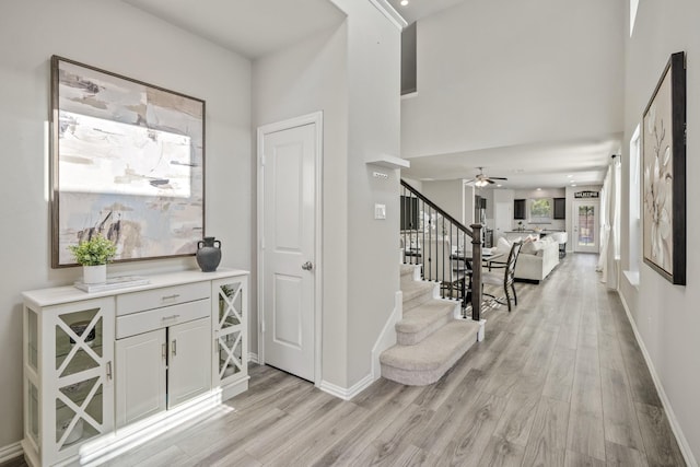 foyer entrance featuring a towering ceiling, ceiling fan, and light hardwood / wood-style floors